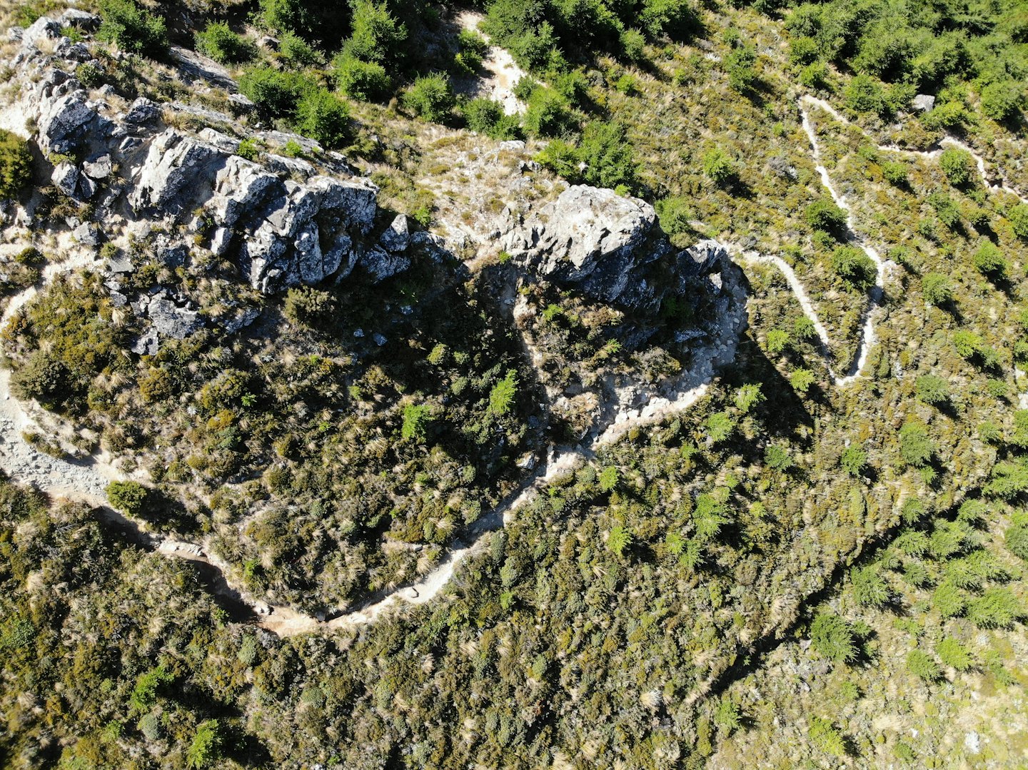 Winding dirt paths cut through rugged mountains and rocky terrain.