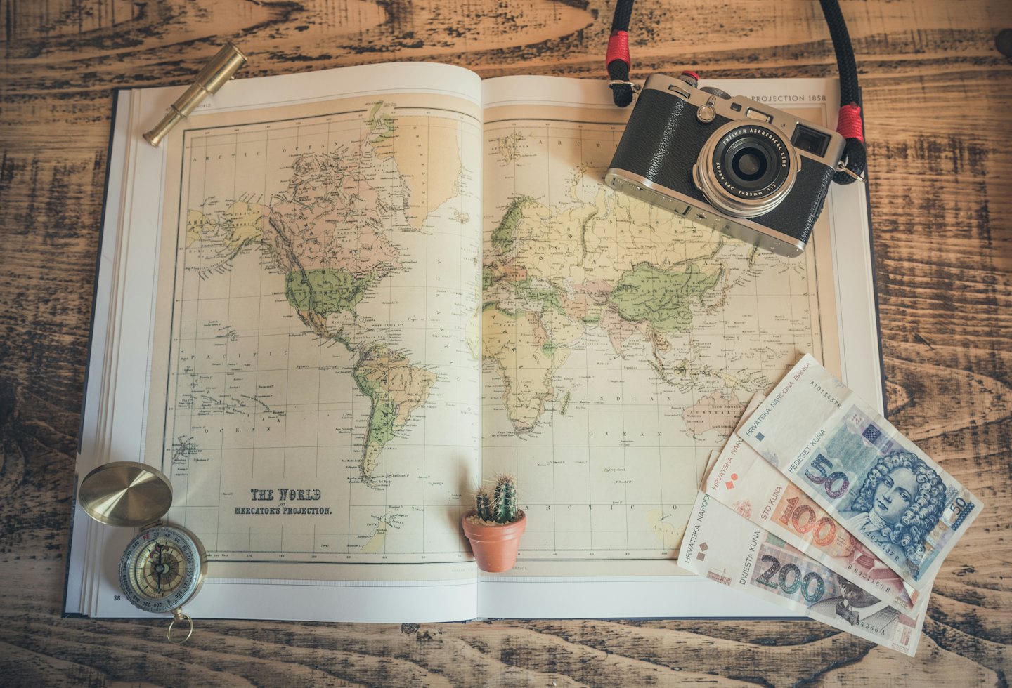 Vintage travel items spread on a wooden table for trip planning.